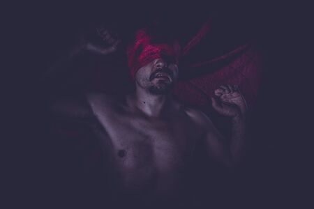 Fantasy, naked man on large red cloth over his eyesの写真素材