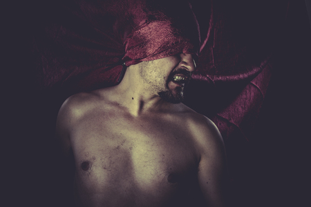 Horror, naked man on large red cloth over his eyesの写真素材