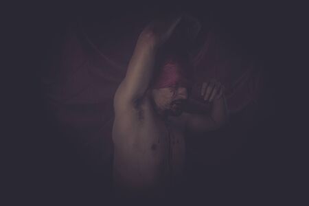 Halloween, naked man on large red cloth over his eyesの写真素材