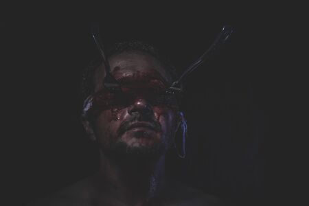 naked man with blindfold soaked in bloodの写真素材
