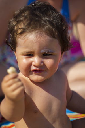 fun little boy playing with sand on the seashore in summerの写真素材