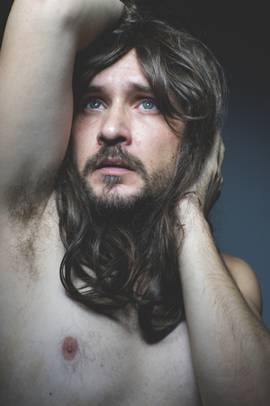 handsome sexy naked man with long dark hair, intense eyes and blue eyesの写真素材