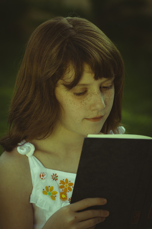 Young beautiful girl reading a book outdoorの写真素材