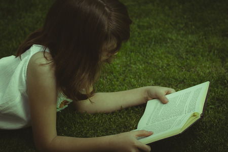 Tale.Young beautiful girl reading a book outdoorの写真素材