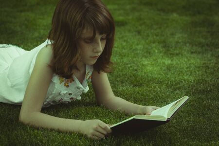 Park.Young beautiful girl reading a book outdoorの写真素材