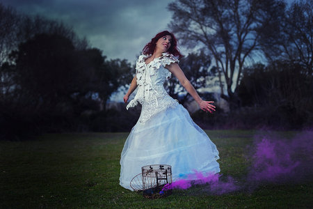 freedom, red-haired girl in white dress of leaves in a wood, iron cage with colored smoke