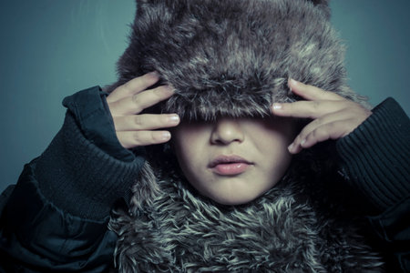 Infant child with fur hat and winter coat, cold concept and stormの写真素材