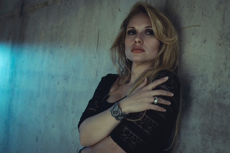 blonde dressed in skintight black costume on a gray cement wallの写真素材