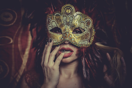 Blonde with gold mask on red cloth embroidered golden thread, mystery and sensuality