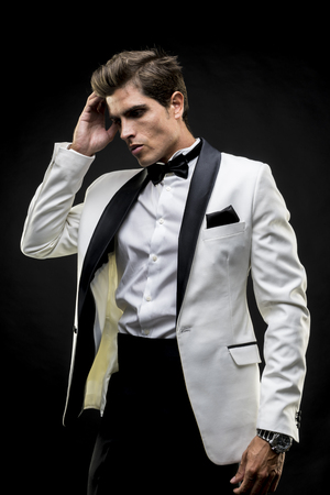 Success, elegant man in a white suit tuxedo with bow tie around his neckの写真素材