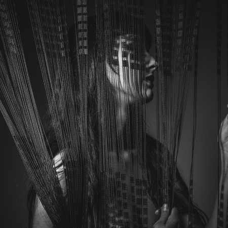 Lady sensual and erotic nude brunette behind a curtain wiresの写真素材