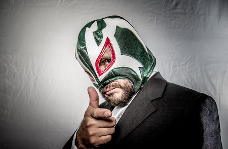 Boss, Angry businessman with mask of Mexican fighter, dressed in suit and tieの写真素材