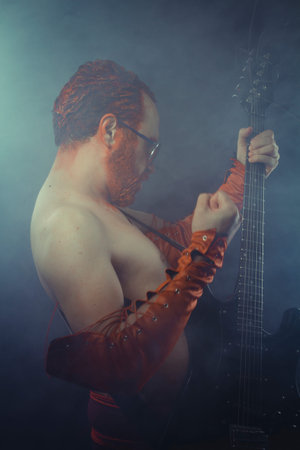 Rock star with electric guitar and concert hall smoke environment