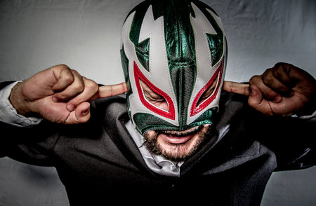 Angry businessman with mask of Mexican fighter, dressed in suit and tieの写真素材
