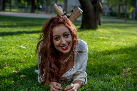 smiling long-haired teenager in a forest or field with green meadowsの写真素材