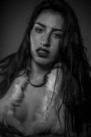Luxury, Beautiful brunette woman with wet hair and dressed in a white fur coat, sensual imageの写真素材