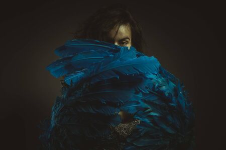 Beautiful latina woman in blue feather bird costume, fantasy and imagination imageの写真素材