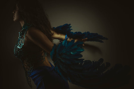 Beautiful latina woman in blue feather bird costume, fantasy and imagination image