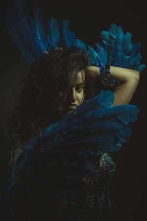 Beautiful latina woman in blue feather bird costume, fantasy and imagination imageの写真素材