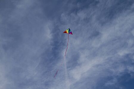 Recreational, Kite of rainbow colors on a blue sky with light white cloudsの写真素材