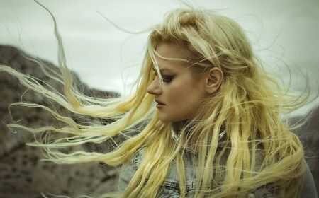Beautiful, blond woman with long hair moved by the wind on a paradise islandの写真素材