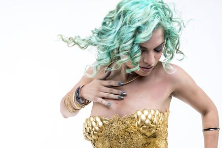 Sexy Latin woman dancing, gold dress and jewels. Young woman with her short green emerald hairの写真素材