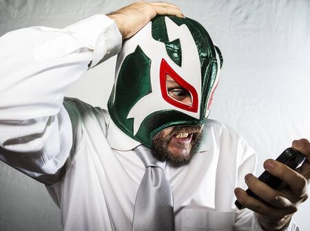 Angry businessman with iron mask on his face, is dressed in suit and tieの写真素材