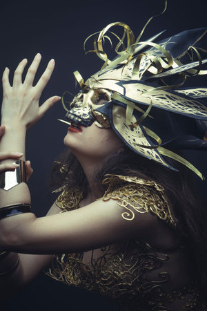 Metallized, Girl in dress made of golden threads with golden mask, beautiful young brunetteの写真素材