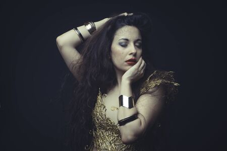 Girl in dress made of golden threads with golden mask, beautiful young brunetteの写真素材