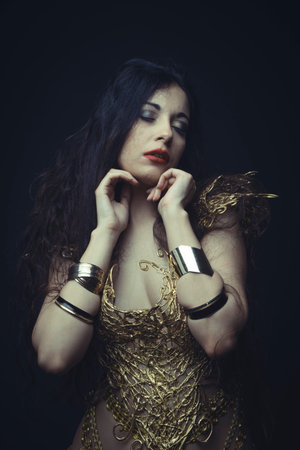 Jewelry, Girl in dress made of golden threads with golden mask, beautiful young brunetteの写真素材