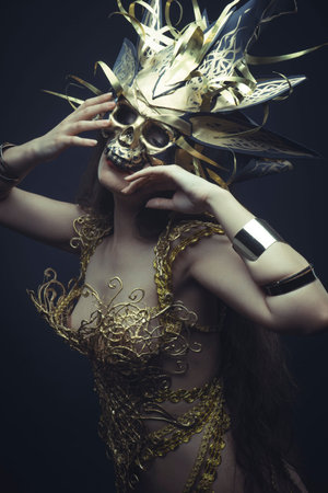 Jewelry, Girl in dress made of golden threads with golden mask, beautiful young brunette