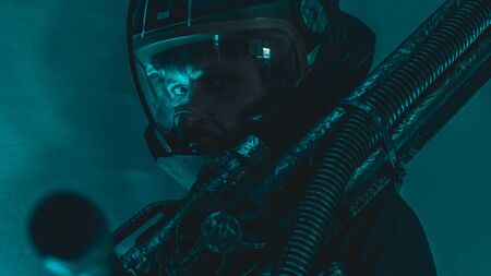 Pilot, man of the future or space with futuristic helmet and fantasy lights, carries a laser weapon in his handsの写真素材