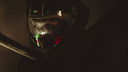 man of the future or space with futuristic helmet and fantasy lights, carries a laser weapon in his handsの写真素材