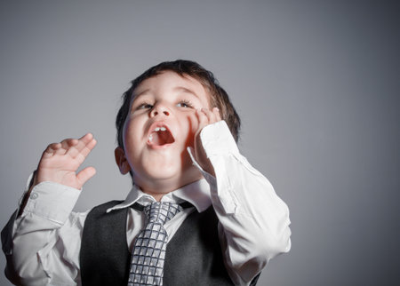 little businessman, brown-haired boy dressed in suit and tie with faces and funny expressionsの写真素材