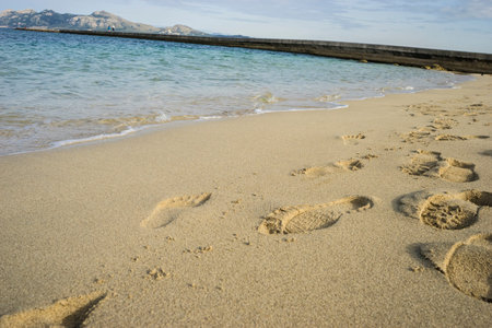 Mediterranean scene, shore of the Mediterranean Sea with barefoot footprints of people in summer
