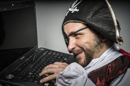 Stealing, hacker, cyber criminal with pirate clothes, attempt to hack a laptopのeditorial素材
