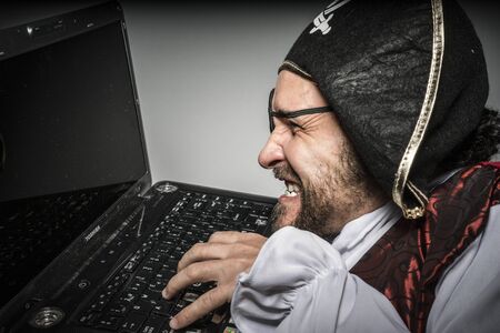 Spy, hacker, cyber criminal with pirate clothes, attempt to hack a laptopのeditorial素材