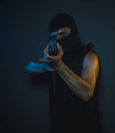 Mafia hit man, armed and dangerous man with balaclava and bulletproof vest, concept killer contractの写真素材