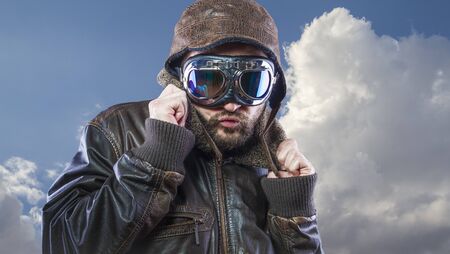 pilot of the 20s with sunglasses and vintage aviator helmet. Wears leather jacket, beard and expressive facesの写真素材