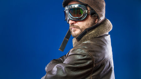 Proud, pilot of the 20s with sunglasses and vintage aviator helmet. Wears leather jacket, beard and expressive facesの写真素材