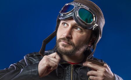 Gentleman pilot of the 20s with sunglasses and vintage aviator helmet. Wears leather jacket, beard and expressive facesの写真素材
