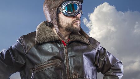 pilot of the 20s with sunglasses and vintage aviator helmet. Wears leather jacket, beard and expressive facesの写真素材