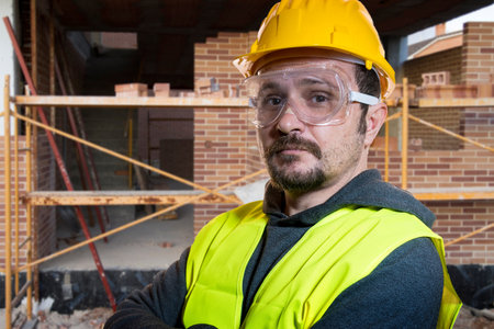 Man dressed in yellow builder helmet with protective glasses ready to start the construction workの写真素材