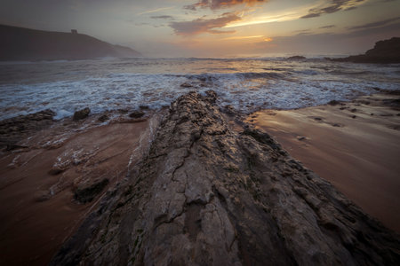 Sunset in Tagle beach. panoramic view of nice colorful huge cliff and sea on the back. Cantabria. Spain.の写真素材