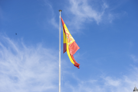 spain flag on a mast in the wind on blue sky backgroundの写真素材