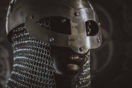 Viking helmet with chain mail of iron on red shield of wood and golden triskelの写真素材