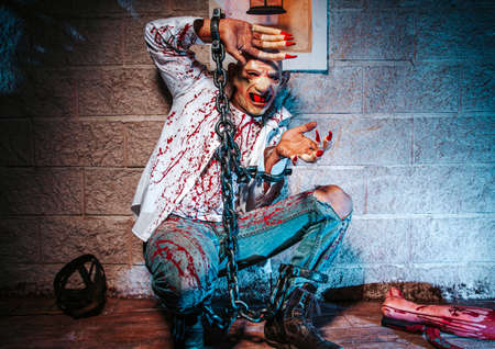 halloween costume, Man chained with blood and knife, Zombie man death the ghost horror drain hand blood skin is screaming darkness and nightmare background of scary fear on hell is monster devil  in halloween festival conceptの写真素材