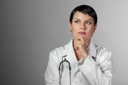 Portrait of an attractive young female doctor in white coat. Smiling medical woman doctor. Isolated over white backgroundの写真素材