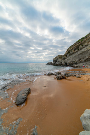 Tranquil scene of Tagle Beach in Cantabria, Spain, showcasing rugged rocks, gentle waves, and an expansive horizon. Perfect for travel, nature, and coastal themes.の写真素材