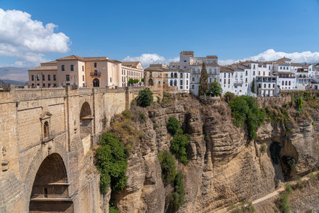 The iconic Puente Nuevo Bridge in Ronda, Spain, gracefully arches over the deep Tajo Gorge, with historic buildings perched on the cliffs. Perfect for themes of architecture, history, and travel.の写真素材